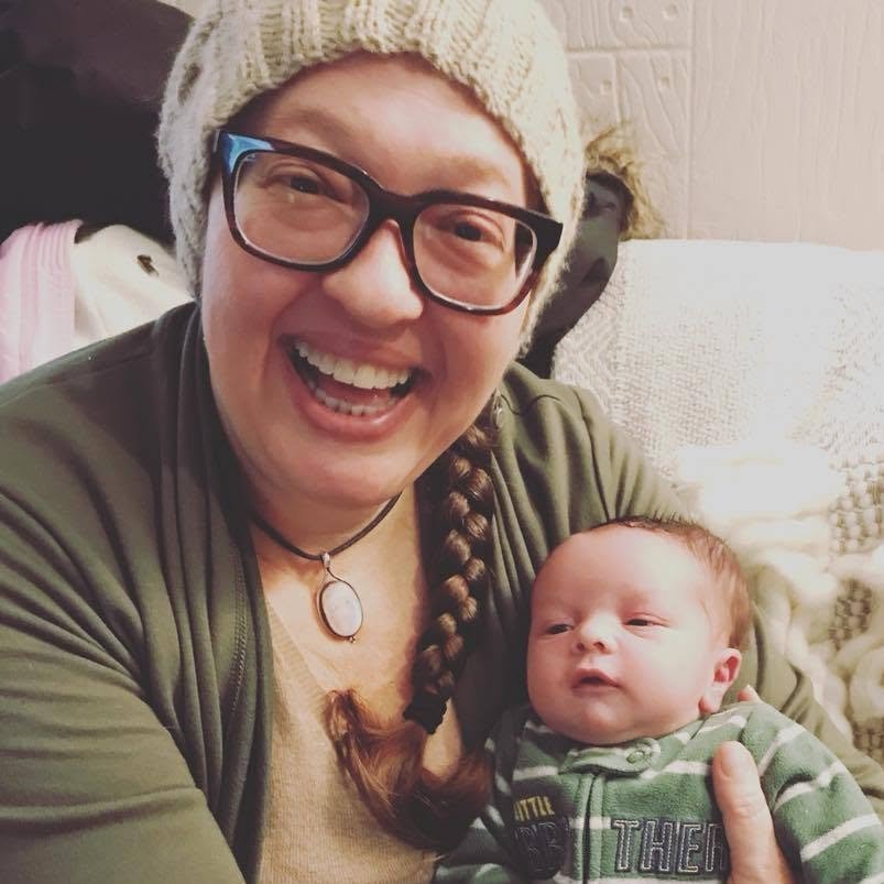 Juliet Dietsch, Licensed Certified Professional Midwife in Louisville, Kentucky, smiling while holding a newborn baby