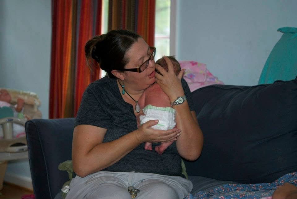Juliet Dietsch, a Louisville home birth midwife, holding a newborn baby during a postpartum visit